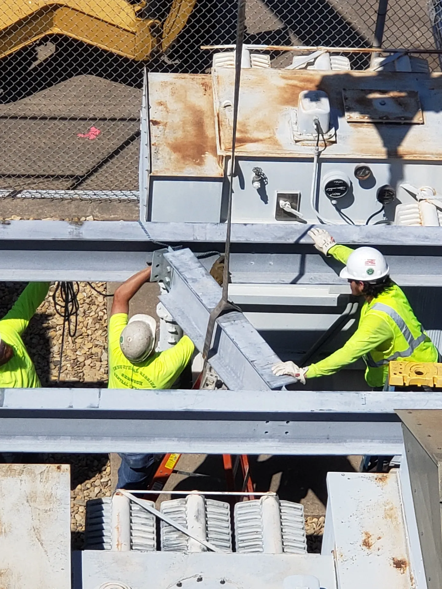 Construction workers installing metal beams outdoors.