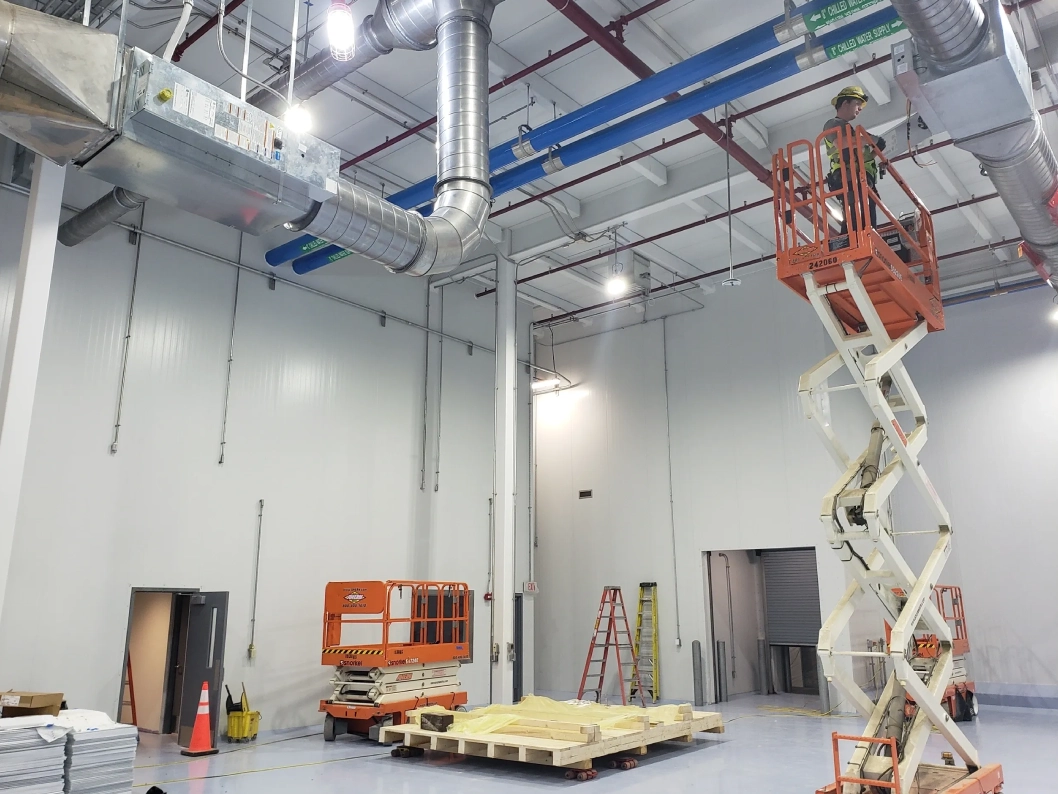 Worker on lift in industrial building interior.