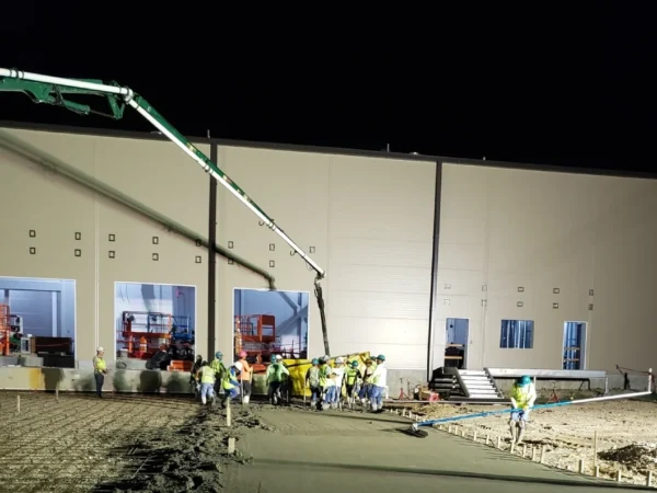 Construction workers pouring concrete at night.