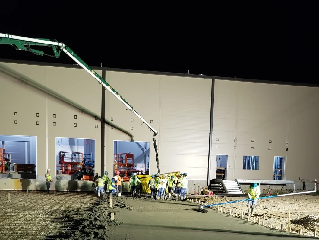 Construction workers pouring concrete at night.