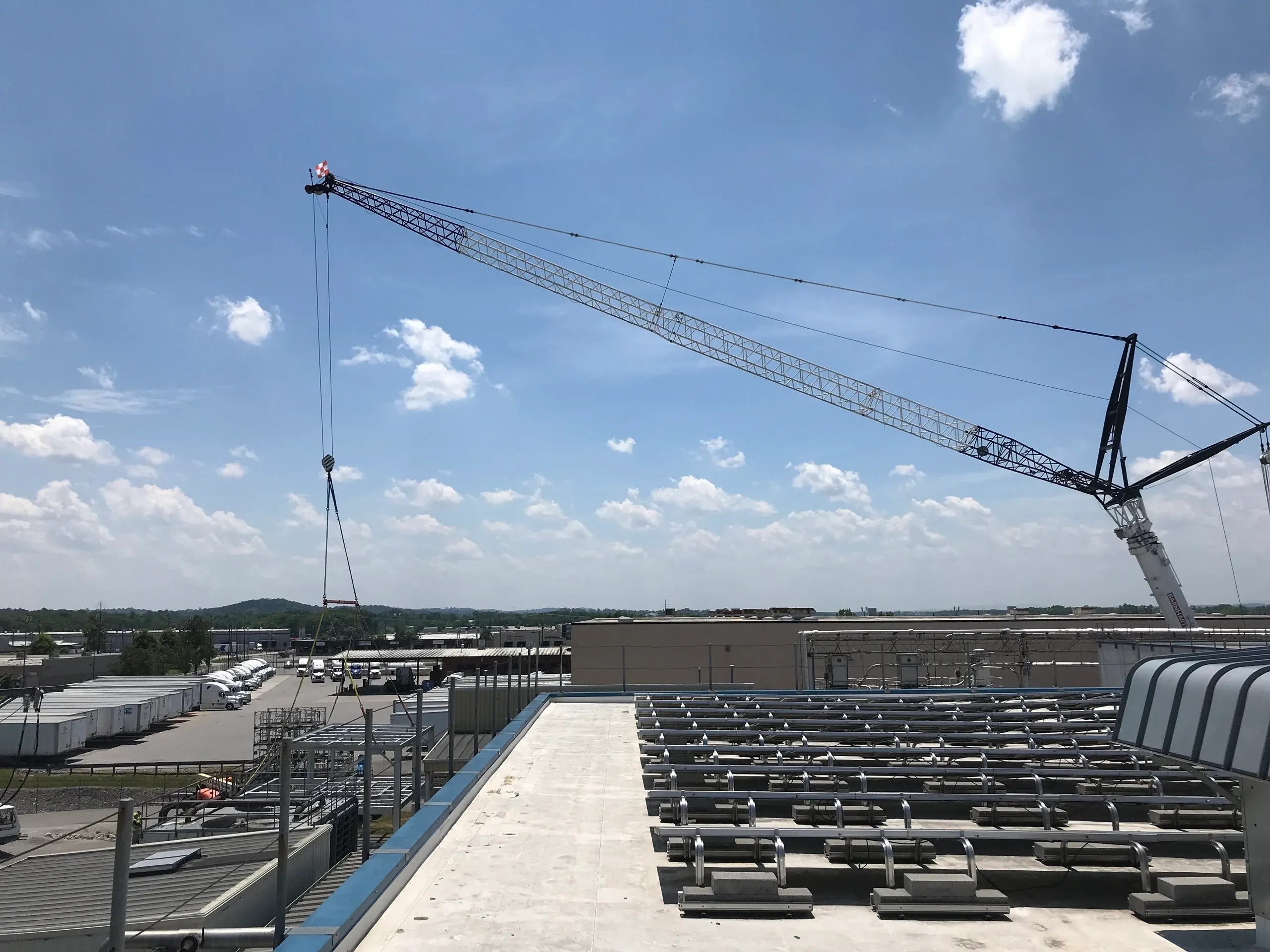 Crane lifting object on industrial rooftop.